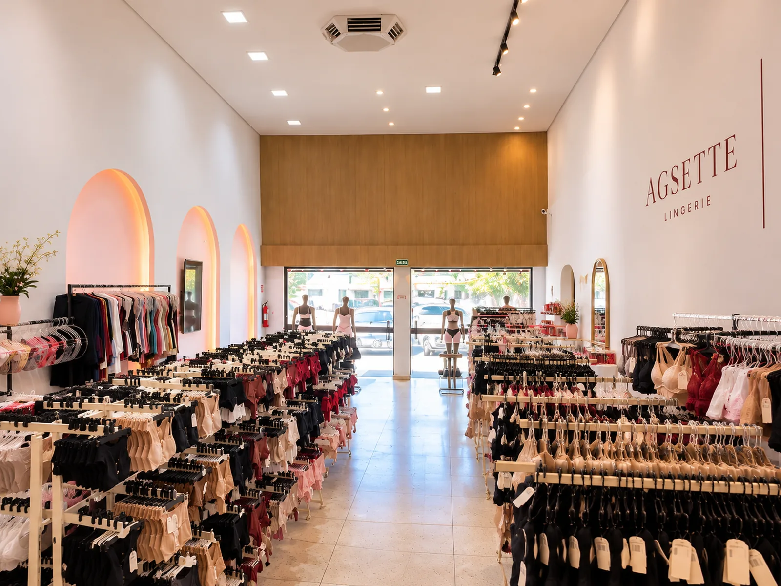 Interior da loja física Agsette Lingerie com peças em renda expostas em araras